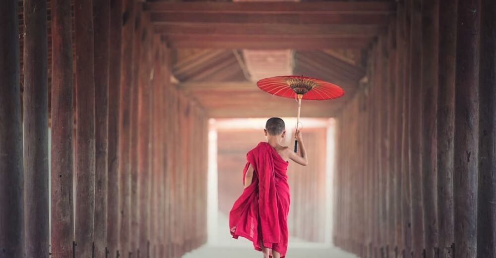 Tradition - Boy Walking Between Wooden Frame While Holding Umbrella